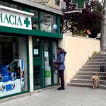 Una mujer en la entrada de una farmacia con su perro
