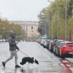 Un joven pasea un perro por el centro de la capital en el segundo día de la entrada en vigor de la limitación total de movimientos salvo de los trabajadores de actividades esenciales, Marta Fernández Jara / Europa Press