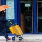 Una cartera, protegida con mascarilla, reparte el correo bajo la lluvia, hoy en Valencia, decimoséptimo día des estado de alarma decretado por el Gobierno