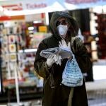 Una mujer compra medicamentos y el periódico en uno de los días de cuarentena