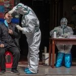 Un trabajador m&eacute;dico con equipo de protecci&oacute;n completo realiza una prueba a un hombre para detectar s&iacute;ntomas de Covid-19 en una calle de Wuhan, China/EFE