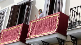 Una mujer habla desde su balcón en Sevilla, engalanado para la Semana Santa Una mujer habla desde su balcón en Sevilla, engalanado para la Semana Santa