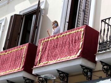 Una mujer habla desde su balc&oacute;n en Sevilla, engalanado para la Semana Santa