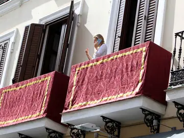 Una mujer habla desde su balcón en Sevilla, engalanado para la Semana Santa Una mujer habla desde su balcón en Sevilla, engalanado para la Semana Santa