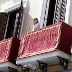 Una mujer habla desde su balcón en Sevilla, engalanado para la Semana Santa