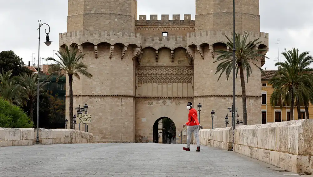 Una persona camina en solitario hacia las Torres de Serranos de Valencia durante el vigésimo cuarto día del estado de alarma decretado por el Gobierno