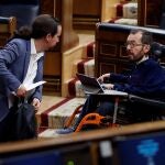 El vicepresidente segundo del Gobierno, Pablo Iglesias (i) conversa con el diputado de Unidas Podemos Pablo Echenique (d) durante el pleno celebrado este jueves en el Congreso para aprobar una nueva prórroga del estado de alarma, en un debate en el que también se abordará la nueva fase que se abrirá en las próximas semanas con el levantamiento progresivo de las restricciones a la movilidad por el coronavirus. EFE/Mariscal POOL