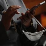 A nun looks at her cell phone while holding a protective face mask as she waits for the start of the Way of the Cross sermon in the metropolitan cathedral closed to the public as a precaution against the spread of the new coronavirus, in La Paz, Bolivia, on Good Friday, April 10, 2020. ( AP Photo/Juan Karita)