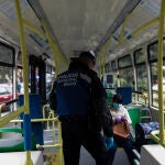 Un policía municipal de Madrid le pide la documentación a una pasajera en un autobús urbanos de la capital ubicado en las inmediaciones de la Glorieta de Pirámides el día en el que se reactiva la actividad laboral no esencial en toda España en las empresas cuyos empleados no puedan teletrabajar cuando se cumple un mes desde el inicio del estado de alarma decretado a consecuencia del coronavirus, en Madrid (España), a 14 de abril de 2020.14 ABRIL 2020;CORONAVIRUS;VIRUS;CONTROL TRAFICO;MADRID;POLICIAJesús Hellín / Europa Press14/04/2020