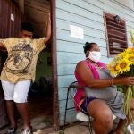 -FOTODELDÍA- AME3460. LA HABANA (CUBA), 17/04/2020.- Una vendedora de flores prepara un ramo de girasoles en el portal de su casa hoy viernes, en La Habana (Cuba). Cuba reportó cuatro nuevas muertes por COVID-19, su mayor cifra de fallecimientos en un día, lo que eleva el conteo a 31 víctimas mortales hasta la fecha, en la que se confirmaron 61 nuevos casos del virus para un acumulado de 923 positivos, informó el Ministerio de Salud Pública (Minsap). EFE/Yander Zamora