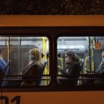 Late night commuters ride a bus in Montevideo, Uruguay, Sunday, April 19, 2020. Starting April 18, wearing a face mask is mandatory for bus travelers, to help contain the spread of the new coronavirus. (AP Photo/Matilde Campodonico)
