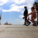 Una mujer y una niña protegidas con mascarilla por el paseo de La Malagueta. Álex Zea / Europa Press