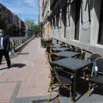 Un hombre con mascarilla pasa junto a una terraza cerrada de un bar en el centro de Madrid