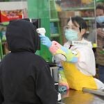 Una trabajadora usa un termómetro de infrarrojos para tomar la temperatura a los clientes durante la reapertura del supermercado Asia, en el barrio madrileño de Usera este miércoles. EFE/Rodrigo Jiménez
