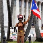 USA1382. SAN JUAN (PUERTO RICO), 01/05/2020.- Una mujer disfrazada ondea la bandera puertorriqueña y sostiene una pancarta que dice "Ten fe" este viernes durante el transcurso de las manifestaciones del Primero de Mayo en San Juan (Puerto Rico). Varias manifestaciones conmemoraron este viernes el Día Internacional del Trabajo en la capital puertorriqueña respetando la normativa sanitaria impuesta por las órdenes ejecutivas de la gobernadora, Wanda Vázquez, para afrontar la crisis de la COVID-19. EFE/Thais Llorca