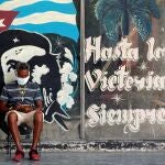 HAB01. LA HABANA (CUBA), 07/05/2020.- Un hombre con tapabocas revisa en su celular, junto a un graffitis con la imagen del guerrillero argentino-cubano Ernesto “Che” Guevara, este jueves en La Habana (Cuba). efe/Ernesto Mastrascusa