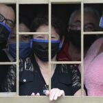 A family peers from their home's window before receiving boxes of free food during a lockdown to prevent the spread of the new coronavirus in Bogota, Colombia, Monday, May 4, 2020. The city government is distributing food to poor people who can't go out to work. (AP Photo/Fernando Vergara)