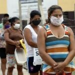 Women line up for a plate of stew for them and their families, at a soup kitchen in Luque, Paraguay, Monday, May 11, 2020. The number of soup kitchens organized by women in the poor neighborhoods of Asuncion is on the rise due to the quarantine set in place to help stop the spread of the new coronavirus. (AP Photo/Jorge Saenz)