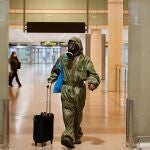 Un pasajero procedente de un vuelo de Londres, llegó este mediodía al aeropuerto de Barcelona ataviado con un mono protector y máscara antigás, hoy viernes que entra en vigor en España la cuarentena obligatoria para todos los viajeros procedentes del extranjero
