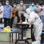 Trabajadores de una fábrica hacen fila en Wuhan para que les hagan un test