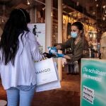 La Comunitat Valenciana inicia la semana ya con todos sus departamentos de salud en fase 1 de desescalada, una medida ansiada por miles de negocios para recuperar poco a poco su actividad y por la sociedad en general para poder reencontrarse con familiares y amigos tras dos meses de confinamiento. En la imagen, una trabajadora de una tienda de ropa aplica gel desinfectante a una clienta