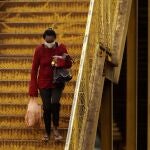 A woman wearing a mask against the spread of the new coronavirus walks down a set of stairs in Valparaiso, Brazil, Wednesday, May 20, 2020. Valparaiso, 40 km. from Brasilia, appears in the statistics as one of the cities in the state of Goias with a high incidence of COVID-19. (AP Photo/Eraldo Peres)