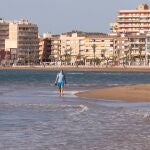 Un hombre con mascarilla camina por la playa