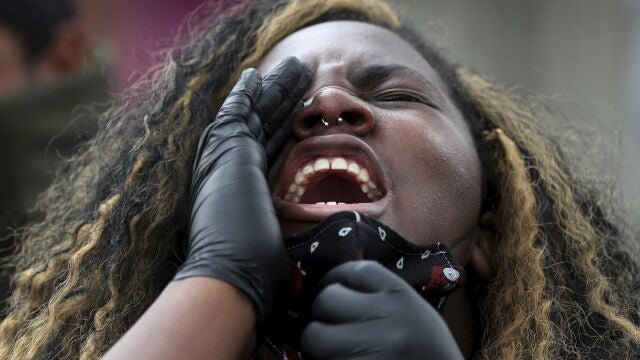 In this Wednesday, June 3, 2020 photo, a woman shouts slogans in front of the U.S. Embassy in Bogota, Colombia, during a rally to protest the death of George Floyd, a black man who was killed in police custody in Minneapolis on May 25. (AP Photo/Fernando Vergara)