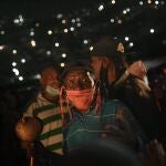 In this Monday, June 1, 2020 photo, a man wearing a face mask amid the new coronavirus pandemic sings and prays during an overnight, Catholic religious procession in the San Agustin neighborhood of Caracas, Venezuela. A small statue of Saint John the Baptist was carried from the home of a resident, who was its custodian for the year, to an outdoor altar, and was later carried to the home of another custodian where it will stay until next year's celebration. (AP Photo/Matias Delacroix)