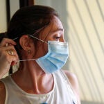 Loli, profesora, usuaria de un implante coclear y miembro de FIAPAS (Confederación Española de Familias de Personas Sordas), se coloca una mascarilla intentando que no se le enganche con el implante