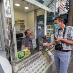 Un hombre compra un cupón a un vendedor de la ONCE