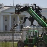 Varios trabajadores retiran parte de un cañón de la base de la estadua de Andrew Jackson frente a la Casa Blanca