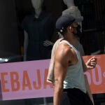 Una persona pasa al lado de un escaparate de una tienda de la capital con carteles de descuentos