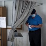 Un hombre coge una papeleta antes de votar en un colegio electoral