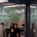 Ciudadanos hongkoneses pasan frente a un póster gigante sobre la nueva ley de seguridad nacional impuesta por China