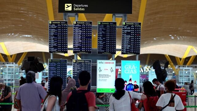 Pasajeros comprueban información sobre su vuelo en la terminal 4 del aeropuerto Adolfo Suárez-Barajas en Madrid