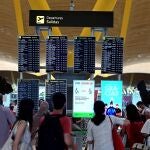 Pasajeros comprueban información sobre su vuelo en la terminal 4 del aeropuerto Adolfo Suárez-Barajas en Madrid