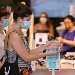 Una mujer se lava las manos con gel hidroalcohólico para entrar en un comercio