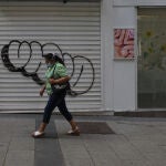 Una mujer pasa por delante de una tienda cerrada durante el confinamiento