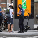 Imagen de un joven que es requerido por la policia municipal para que les muestre la documentación de su patinete eléctrico.
