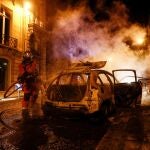 Un bombero apaga las llamas de un coche incendiado en París tras la final de la Champions, que el PSG perdió contra el Bayern Múnich