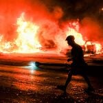 La silueta de un hombre ante varios coches incendiados durante la segunda noche de disturbios tras el tiroteo de Jacob Blake por parte de agentes de la Policía en Kenosha (Wisconsin)