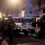 Police officers stand guard near two bodies outside of a disco in Lima, Peru, Sunday, Aug. 23, 2020. Officials said over a dozen people died in a stampede at a disco in Peru after a police raid to enforce the country's lockdown during the coronavirus pandemic. (AP Photo/Diego Vertiz)