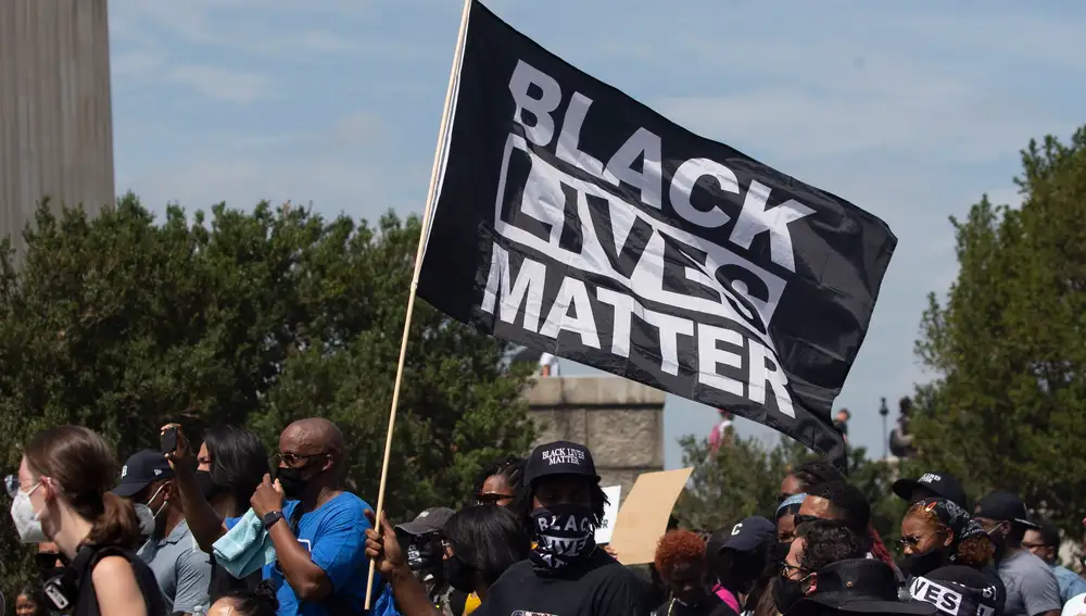 Participantes portan una mandera del movimiento «Black Lives Matter» contra el abuso policial a los negros