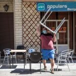 Un hombre recoge las sillas y mesas de la terraza de su negocio en la localidad valenciana de Benigànim (Valencia)