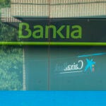 Imágenes de una sucursal bancaria de Bankia en la que se ve de fondo una de La Caixa por su inminente fusión.