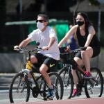 Una pareja con mascarillas para prevenir a propagación del coronavirus transita en bicicletas