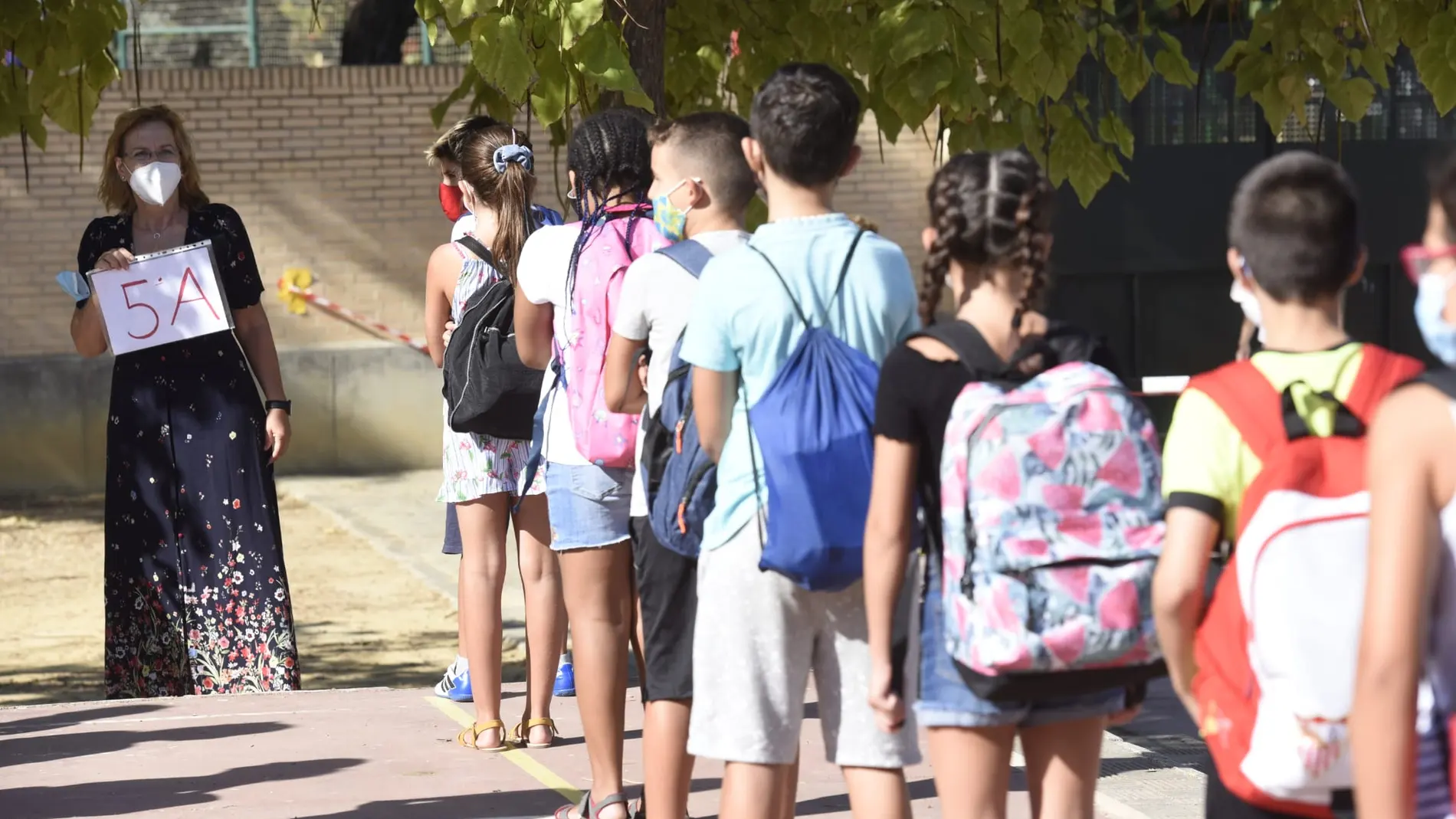 Alumnos de un colegio de Sevilla hacen cola ante una profesora