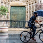 Un ciclista  paraguas por  la  Av. de la Constituci&oacute;n, en una ma&ntilde;ana lluviosa en  Sevilla