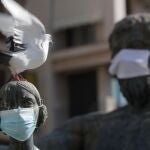 Una paloma se posa este martes sobre una escultura, provista de mascarilla, en el centro de la ciudad de Valencia.